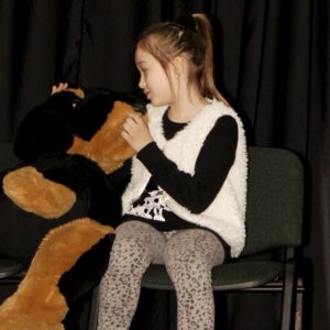 Dziewczynka grająca na scenie z pluszowym misiem