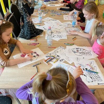 grupa dzieci rysująca i kolorująca kollorowanki z postaciami z bajek podczas balu karnawałowego