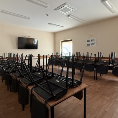 sala świetlicy wiejskiej stoły krzesła i telewizor pokazana od wejścia