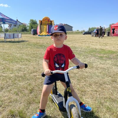 mały chłopiec na rowerze w czerwonej koszulce i czapce z daszkiem