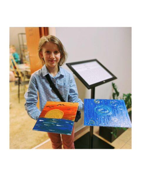 Dziewczynka z obrazkami, na których jest namalowany krajobraz