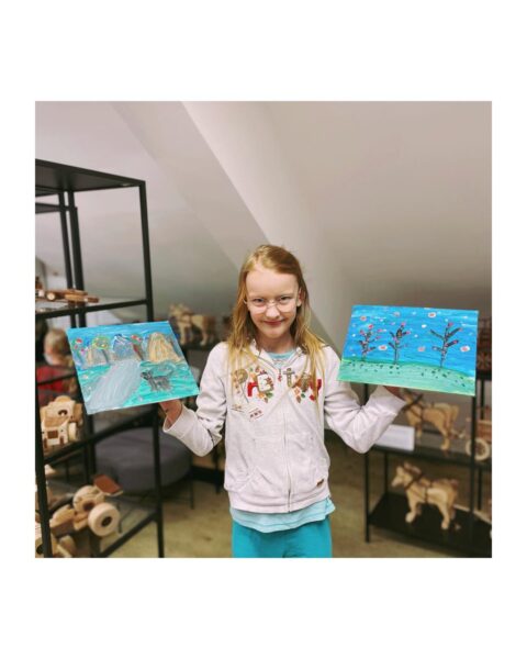 Dziewczynka z obrazkami, na których jest namalowany krajobraz i drzewa
