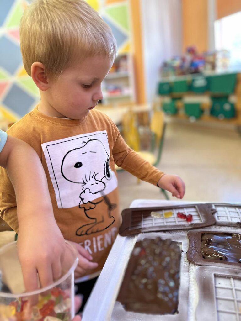 Na zdjęciu widzimy chłopczyka, który dekoruje swoją czekoladę.