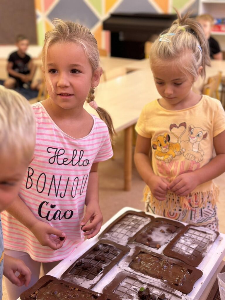 Na zdjęciu widzimy dziewczynki, które są w trakcie dekorowania czekolad.