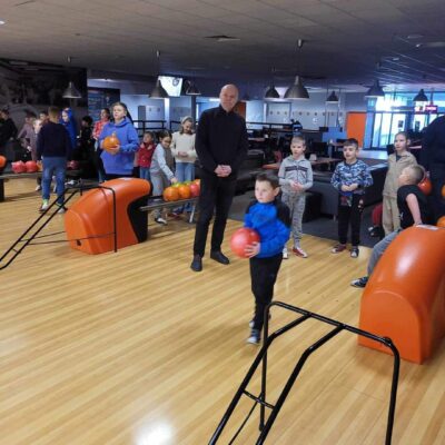 Opiekun z dziećmi tłumaczący zasady gry w Bowling.