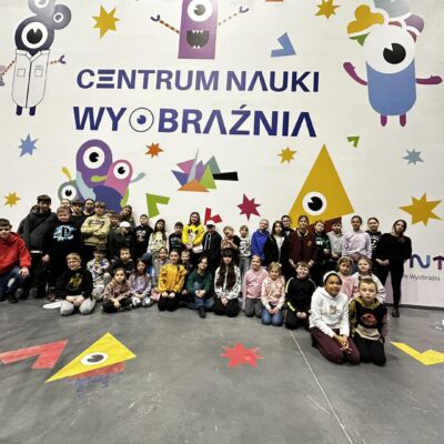 Grupa uczestników wycieczki pozująca do zdjęcia grupowego w Centrum Nauki Wyobraźnia.