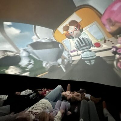 Dzieci w kinie sferycznym oglądające bajkę naukową.