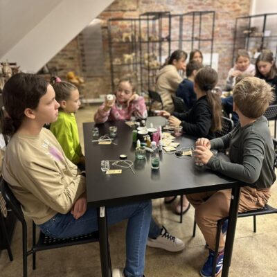 Grupa dzieci na warsztatach z tworzenia świec sojowych.
