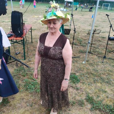 Pani w kapeluszu z żółtymi kwiatami i ptakiem.