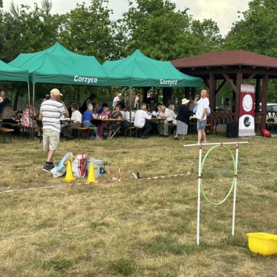 Seniorzy siedzą przy stołach i jedzą.