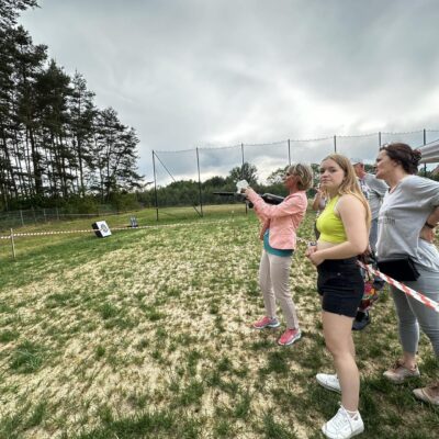 Seniorka oddaje strzał z painball do celu.