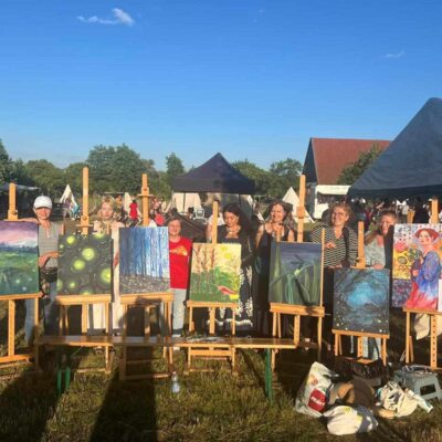 Obrazy na sztalugach wraz z artystkami prezentującymi je.