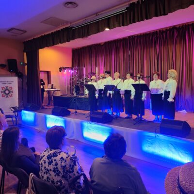 Kobiety śpiewają na scenie do mikrofonów