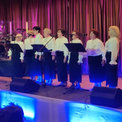 Kobiety śpiewają na scenie do mikrofonów