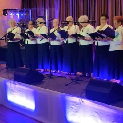 Kobiety śpiewają na scenie do mikrofonów