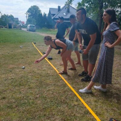 Zawodnicy grają w bule na boisku. Kobieta oddaje rzut.