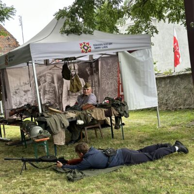 Mężczyzna leży na trawie i przymierza się do broni