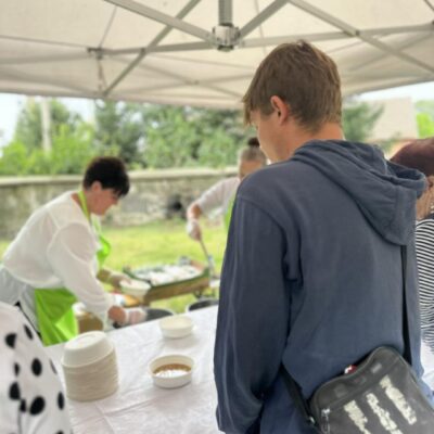 Kobieta rozlewa grochówkę ludziom