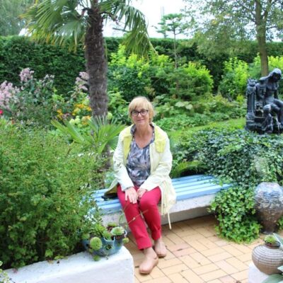 Anna Rawska siedząca na ławce w swoim ogrodzie