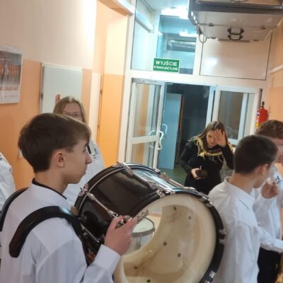 Chłopiec trzymający bęben, czeka na wejście na scenę. W tle reszta zespołu.