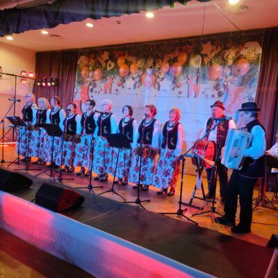 Zespół Osieczanki na scenie w folkowych sukienkach. Mężczyzna gra na akordeonie.