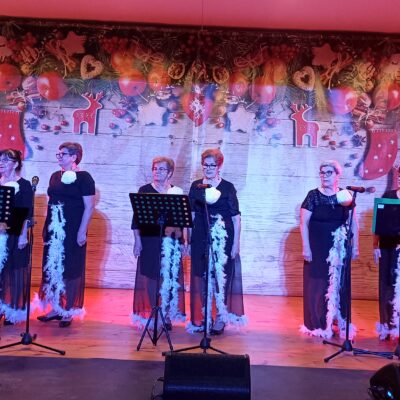 Zespół Lejdis na scenie. Kobiety w sukniach czarnych z piórami.