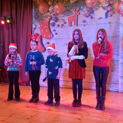 Dziecięcy Zespół wokalny. Cztery dziewczynki i jeden chłopczyk w świątecznych strojach na scenie.