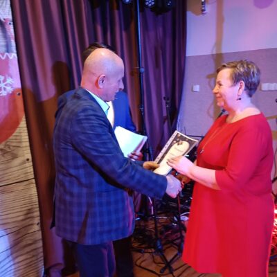 Radny Jerzy Tadla wręcza podziękowanie uczestnikowi chóru.