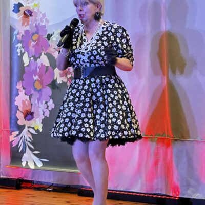 Kobieta na scenie śpiewa w biało czarnej sukience.