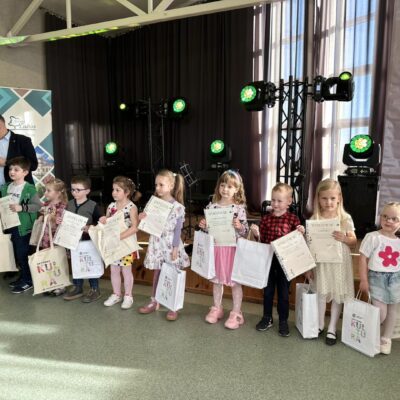 Dzieci z nagrodami za konkurs pod sceną podczas zdjęcia grupowego