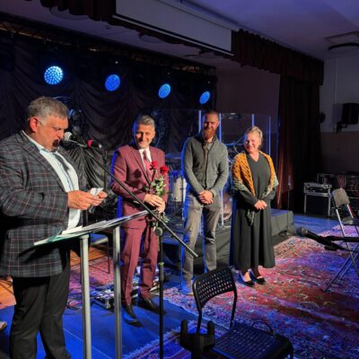 Radny Norbert Grabowski czyta na scenie wyniki z koperty.