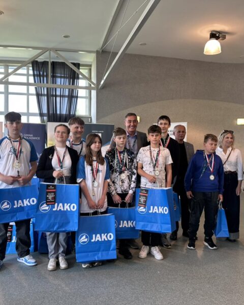 Zawodnicy turnieju z medalami i pucharami oraz nagrodami pozują do wspólnego zdjęcia. 