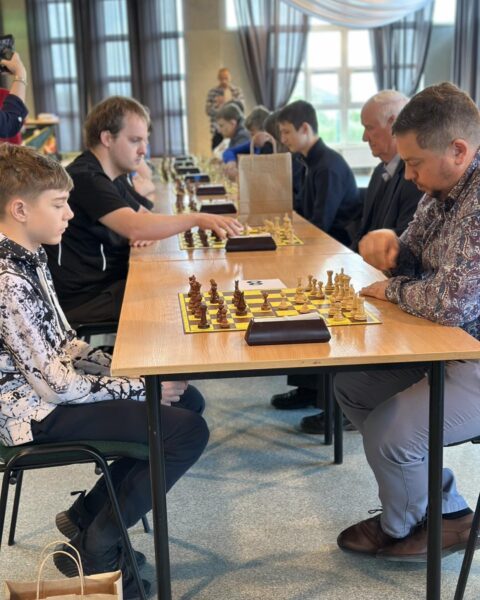 Zawodnicy grają w szachy przy stole nr 1. Chłopiec i mężczyzna. 