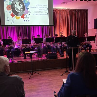 Orkiestra dęta w tle na scenie. prezentacja na ekranie.