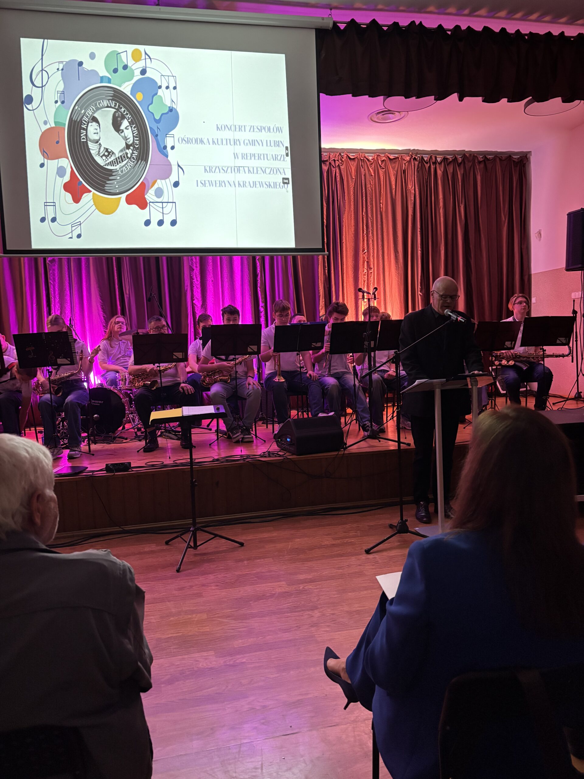 Orkiestra dęta w tle na scenie. prezentacja na ekranie.