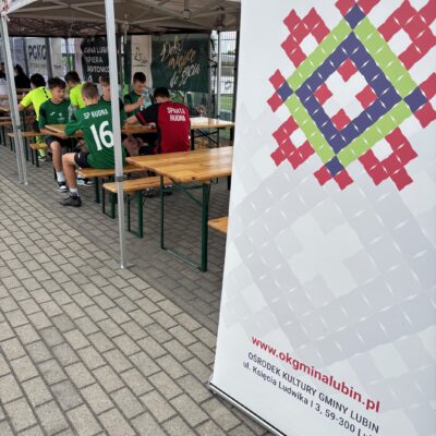 BANER OKGL W TLE ZAWODNICY JEDZĄ POSIŁEK