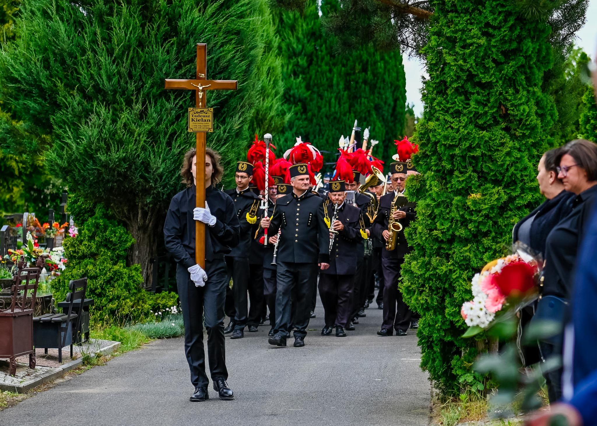 Mężczyzna niesie krzyż za nim w marszu orkiestra dęta podczas pogrzebu