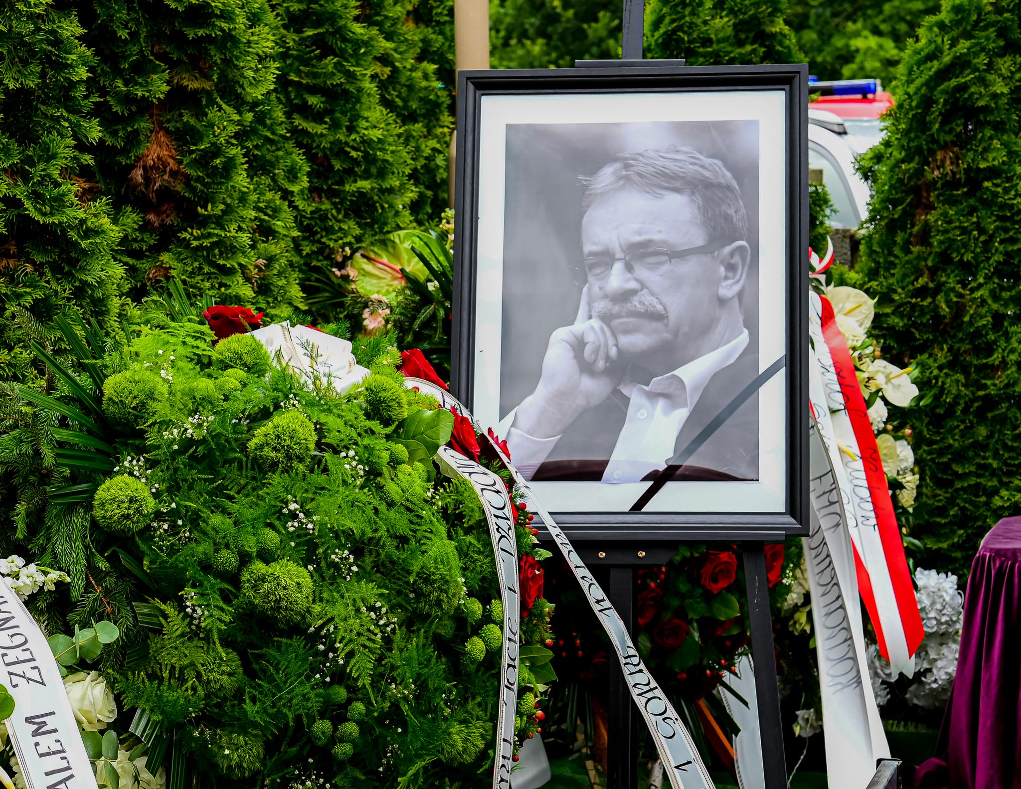 Zdjęcie Tadeusza Kielana na sztaludze. Wokół kwiaty.