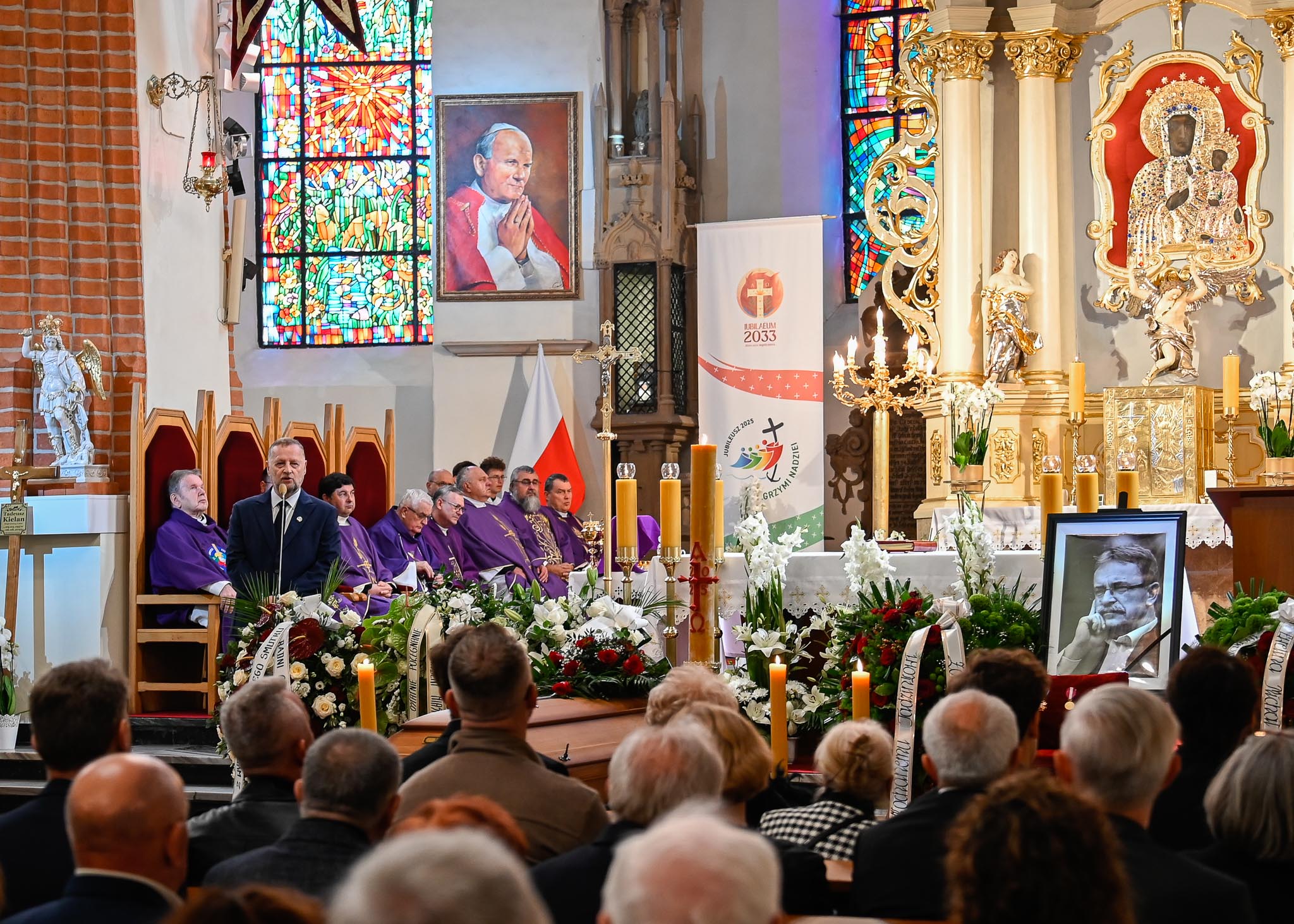 Ceremonia pogrzebowa, ludzie siedzący w ławkach.