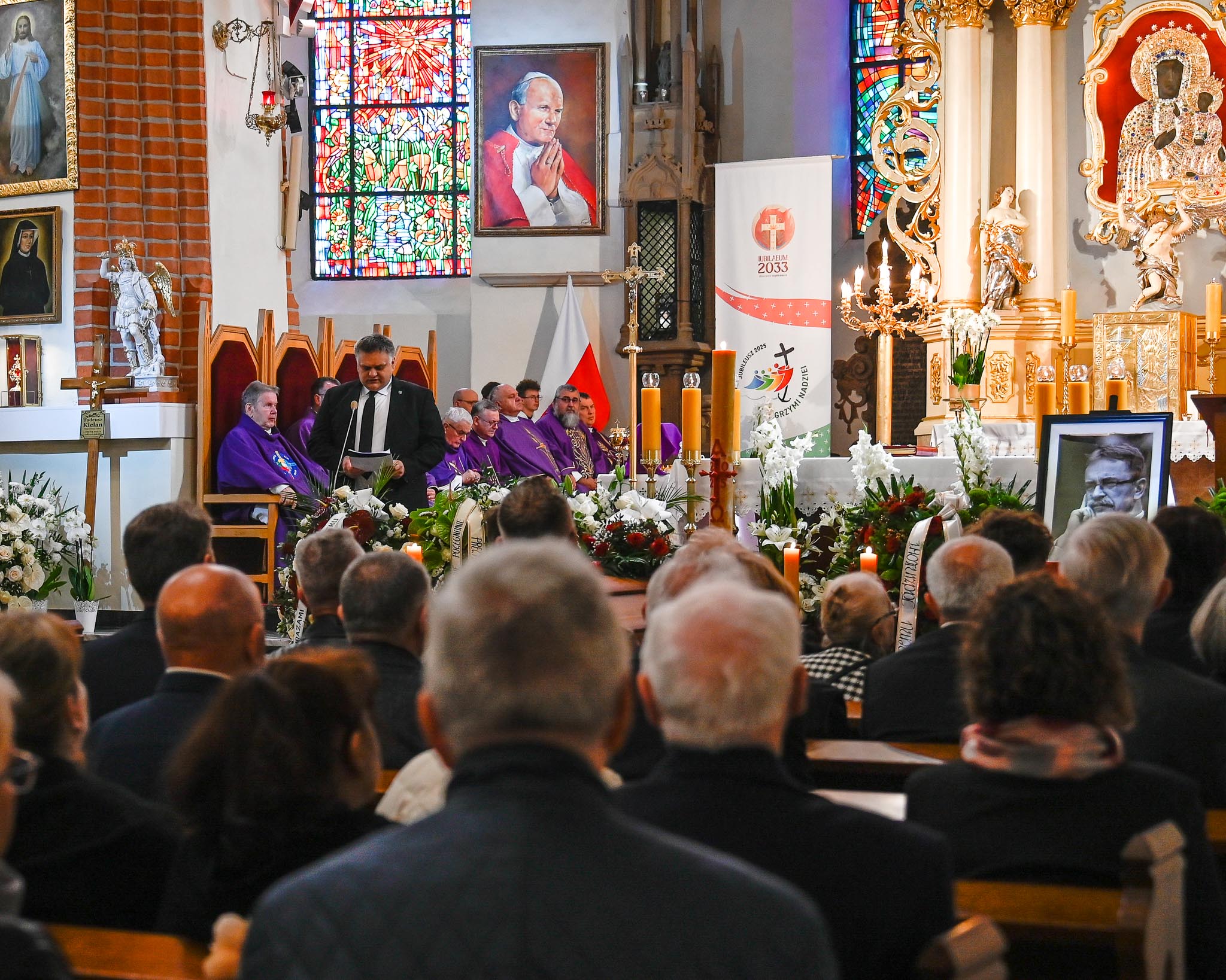 Ceremonia pogrzebowa, ludzie siedzący w ławkach.