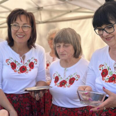 Trzy kobiety w białych bluzkach z czerwonymi kwiatami.