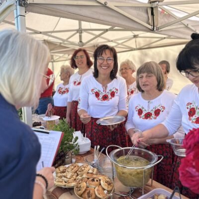 Trzy kobiety prezentują Pani z jury zupę.