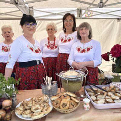 Kobiety z zespołu zachęta przy swoim stanowisku z zupą.