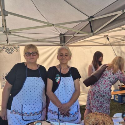 Dwie kobiety w fartuchach pozują do zdjęcia