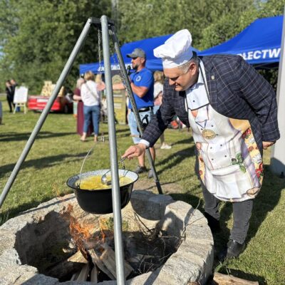 Radny Norbert Grabowski miesza zupę nad paleniskiem.