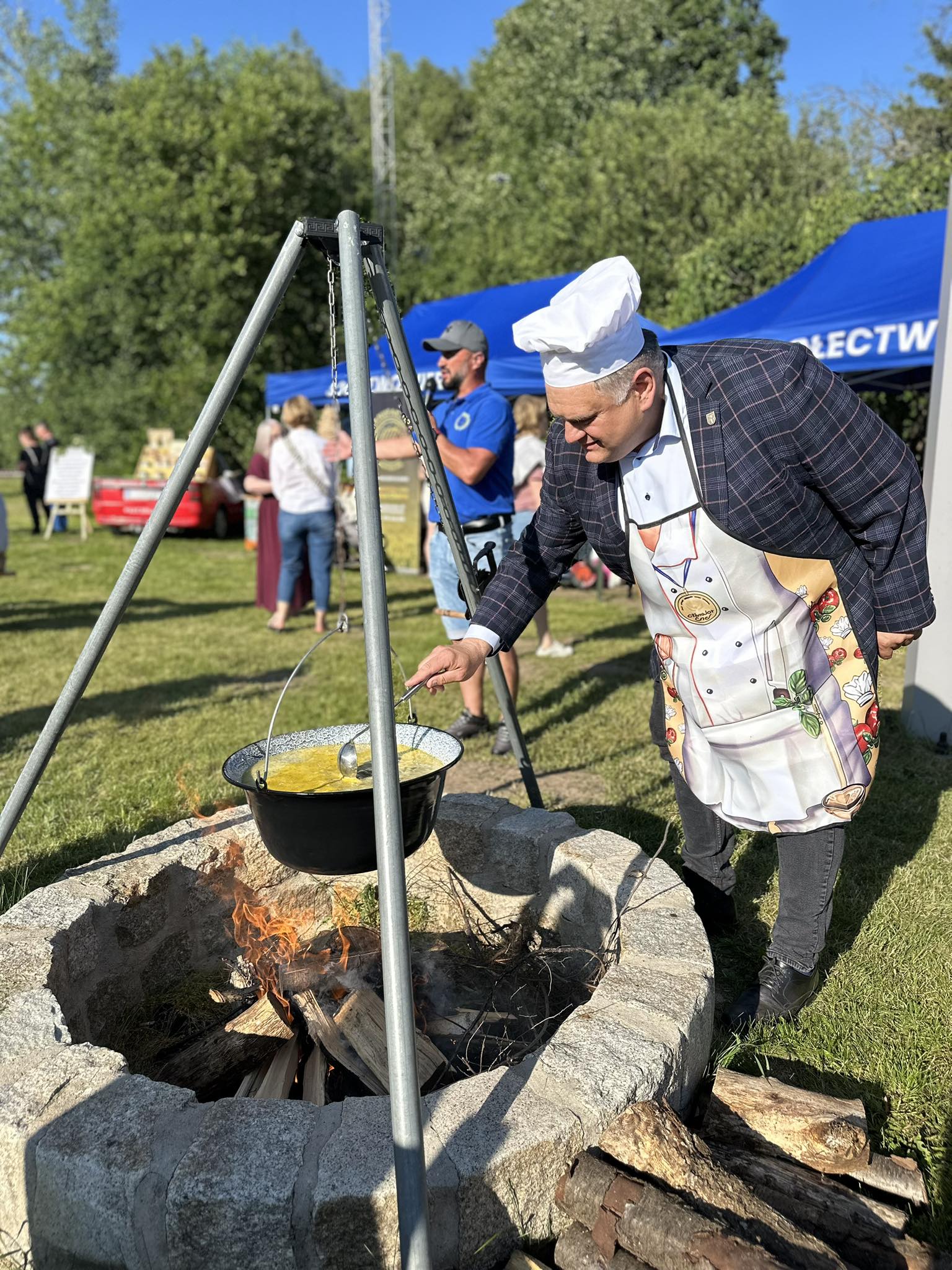 Radny Norbert Grabowski miesza zupę nad paleniskiem.