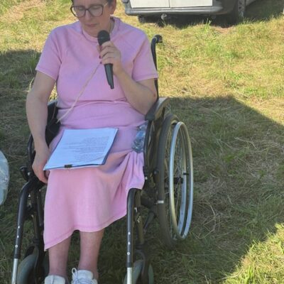 Kobieta na wózku z mikrofonem w rękach.