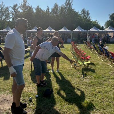 Mężczyzna rzuca kulą drugi go obserwuje.