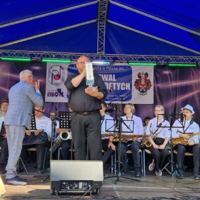 Kapelmistrz z statuetka na scenie mówi do mikrofonu