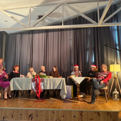 aktorzy przy stole na scenie siedzą i rozmawiają